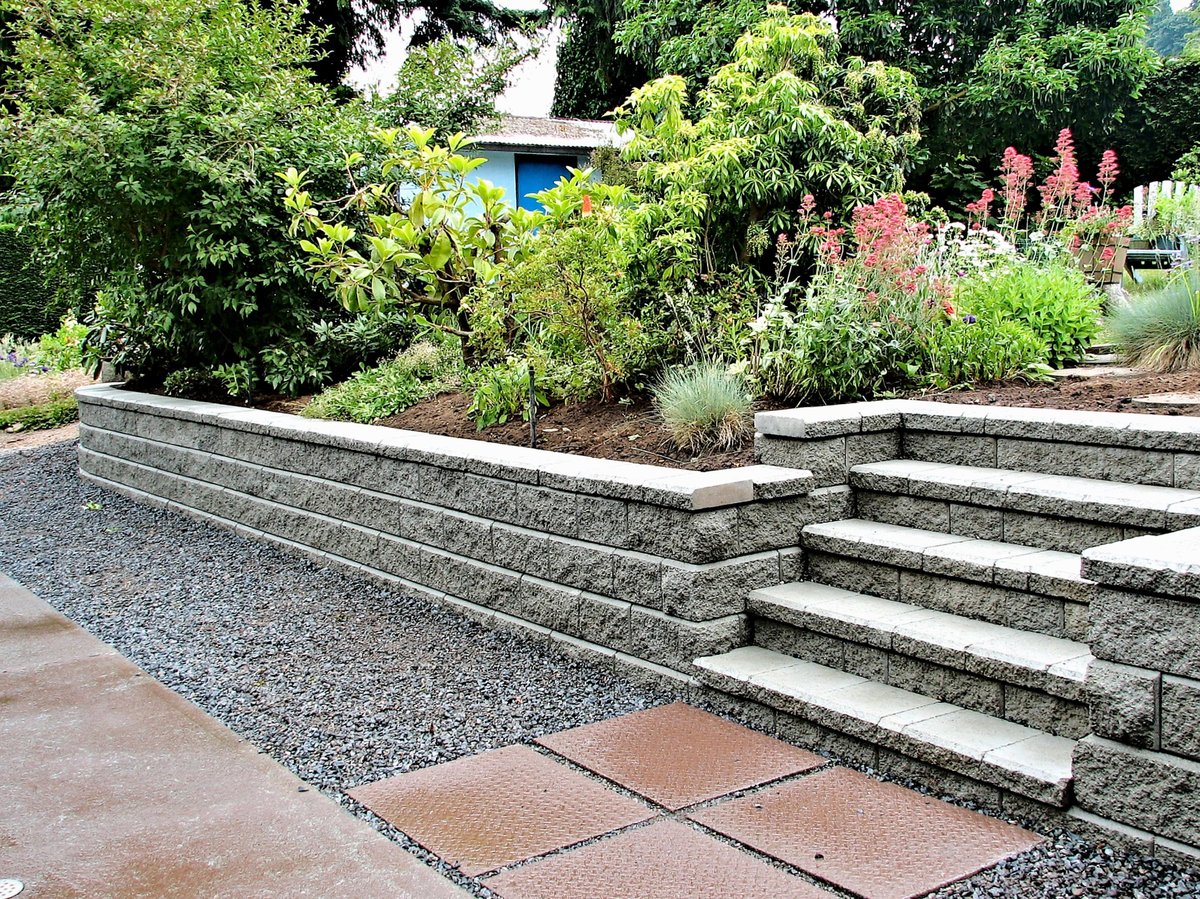 A natural stone retaining wall with built-in steps and stepping stones, completed residential hardscape