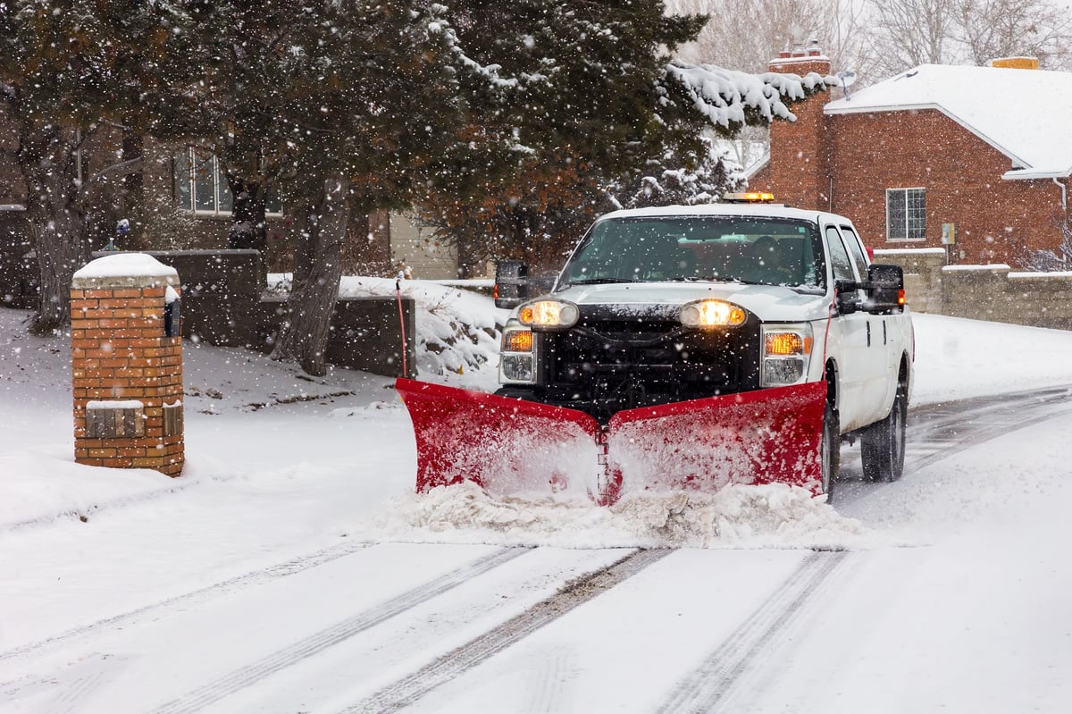 A snowplow clearing a residential street after a New England winter storm, professional snow management