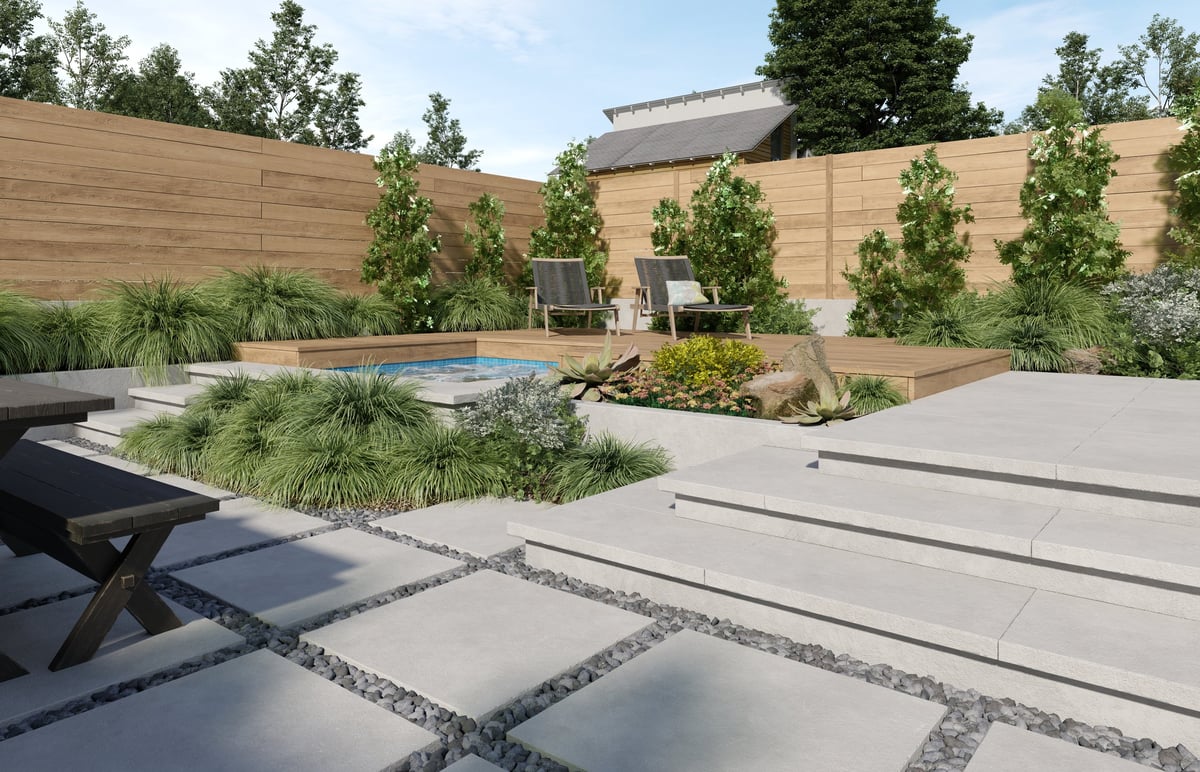 A polished modern backyard with a stone patio, green lawn, and shaped garden beds, finished landscape result